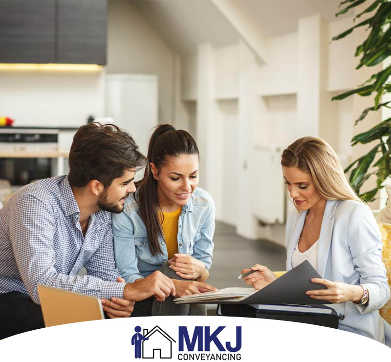 Professional conveyancing team at MKJ Conveyancing office discussing property transfer documents and providing expert property transfer services on about us section on homepage